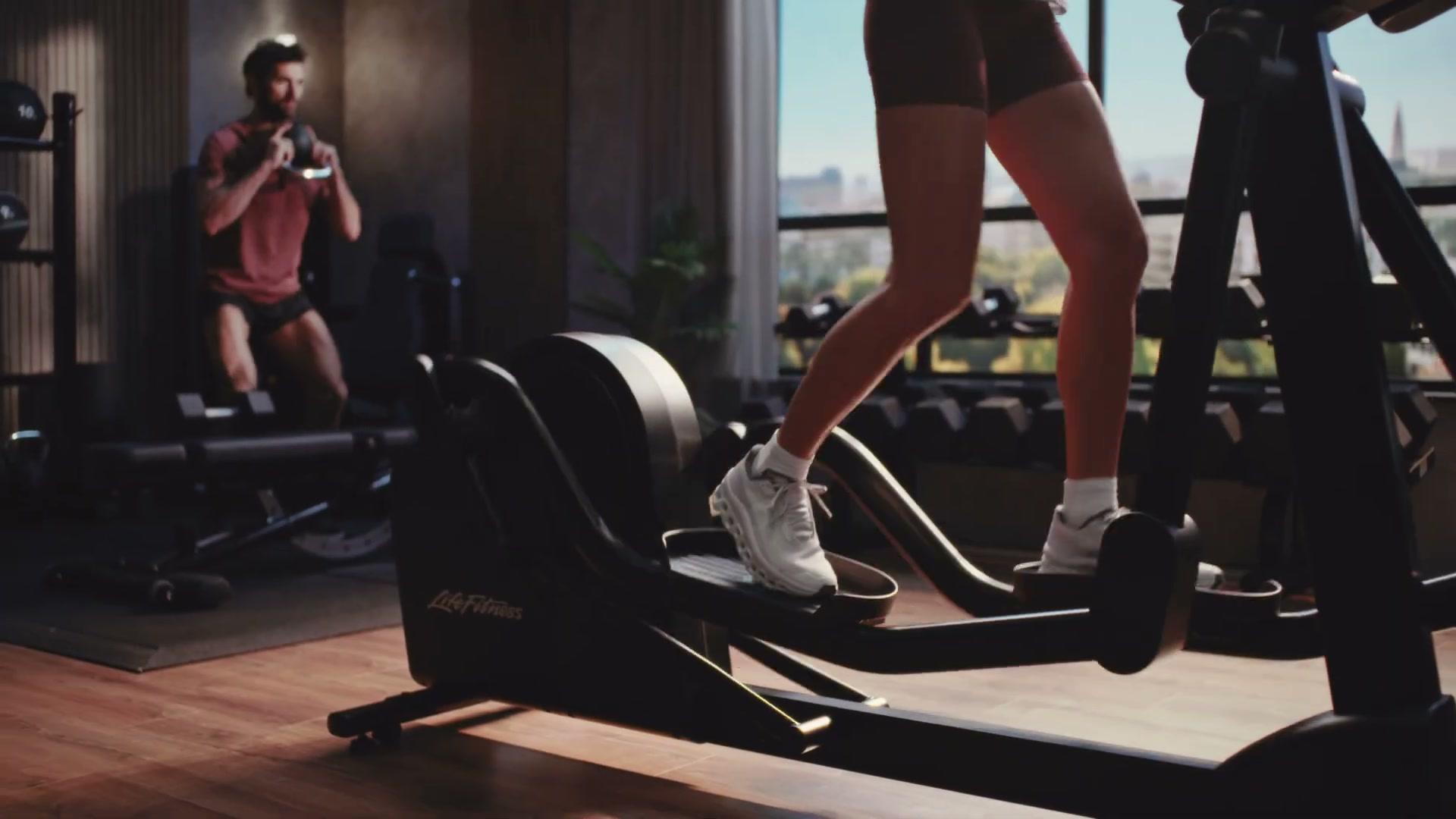 Life Fitness Atmos elliptical with crew member visible behind, behind-the-scenes from the studio shoot