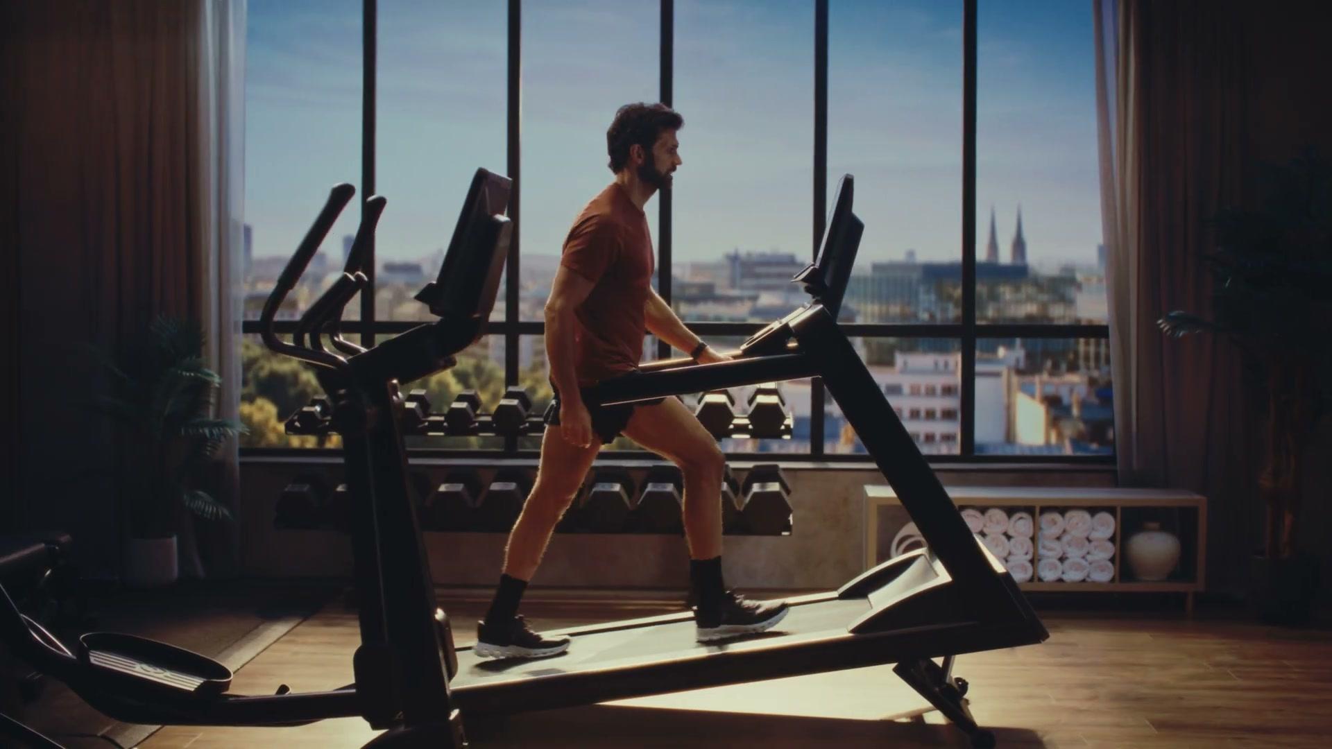 Life Fitness Atmos treadmill in daylight hotel-gym scene with city skyline