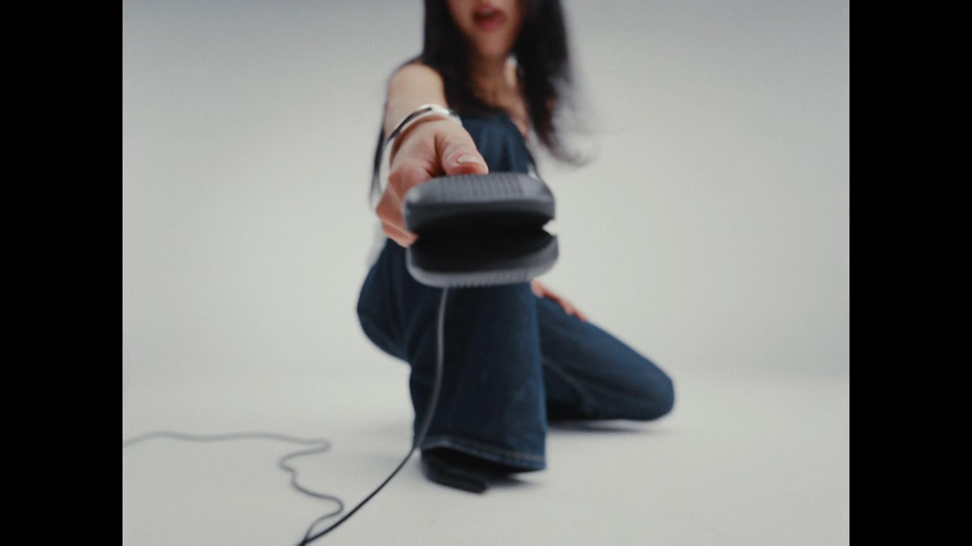 Low-angle motion-blurred shot of model in baggy jeans flipping hair forward and using Cloud Nine hairdryer.
