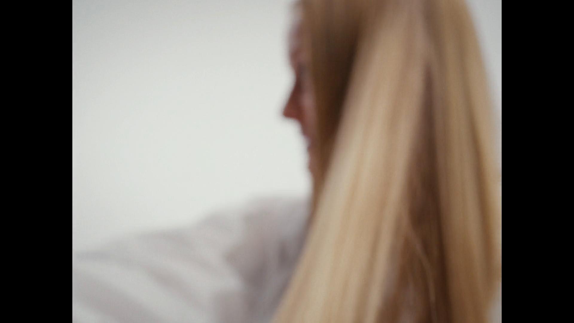 Cloud Nine black straightener gliding through long blonde hair on pale background.