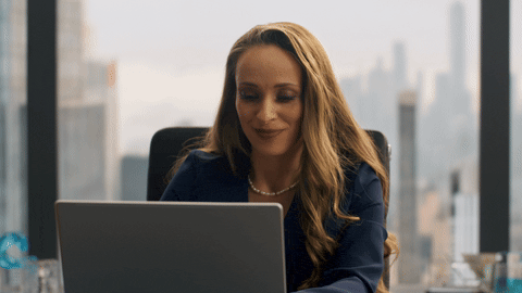 Close-up of the female lawyer with a small confident smile, looking down at her laptop in the calm contrast world.