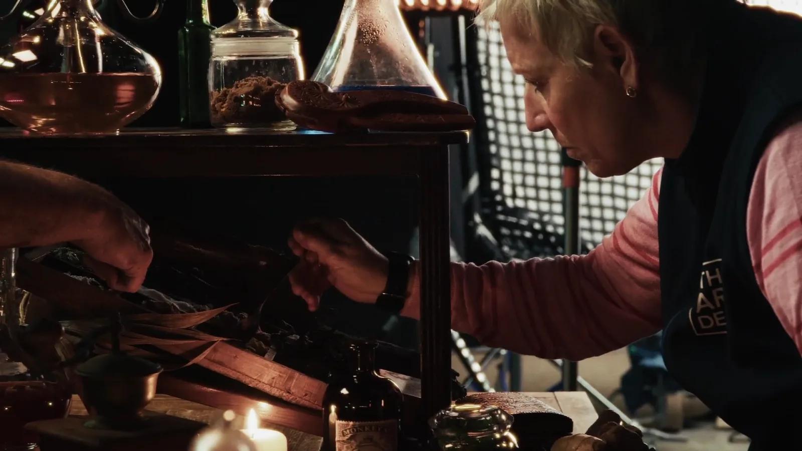Set stylist from The Art Dept arranges hand-finished props on a candlelit table.